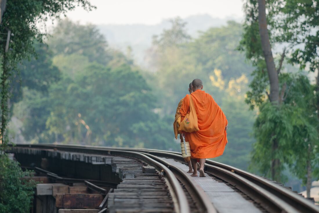 Buddhist monks walking along the bridge at Death Railway, Kanchanaburi, Thailand