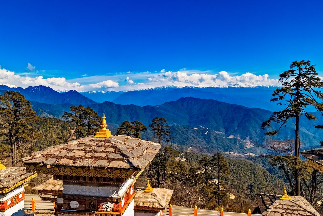 View looking out across Dochula Pass with memorial chortens in Bhutan mountains 
