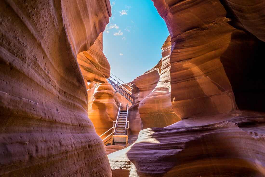 Sun shining down into the lower Antelope Canyon, showing the staircase and blue skies in Arizona, USA
