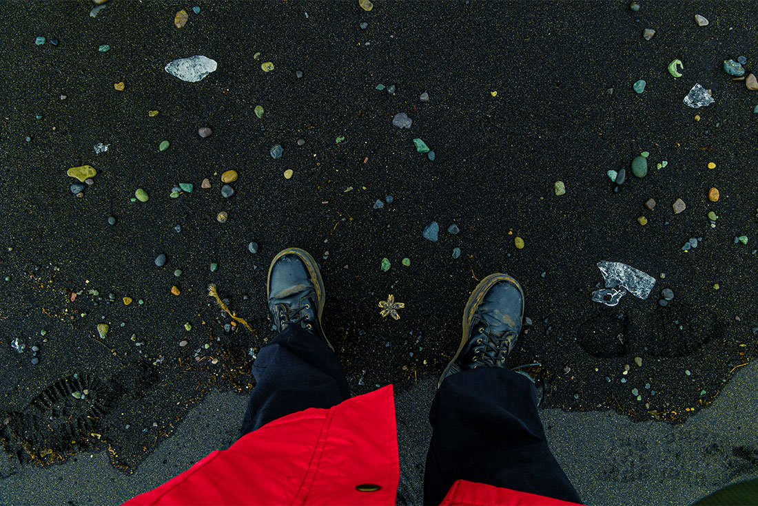 Standing on Jokulsarlon black sand beach with ice and bits of sea debris