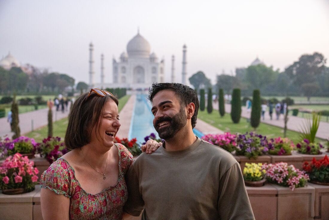 Two travellers laugh together standing in front of the Taj Mahal near Agra India