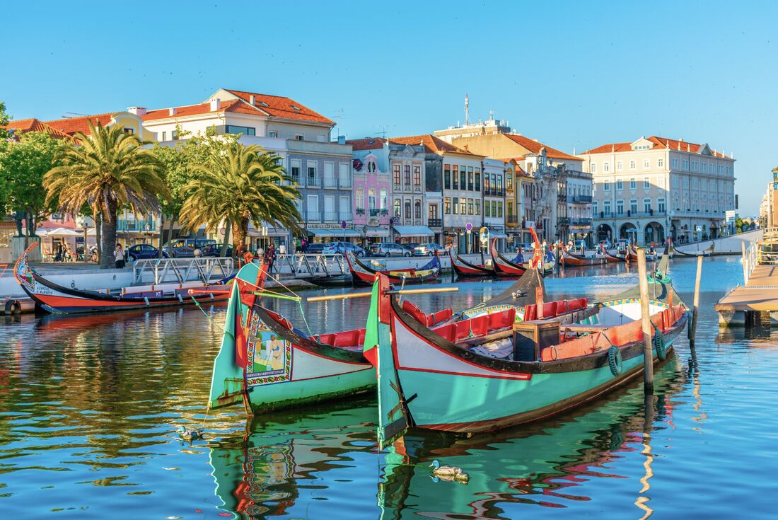 Moliceiro boats in the canals of Aveiro Portugal with the town square and classic Portuguese architecture beyond