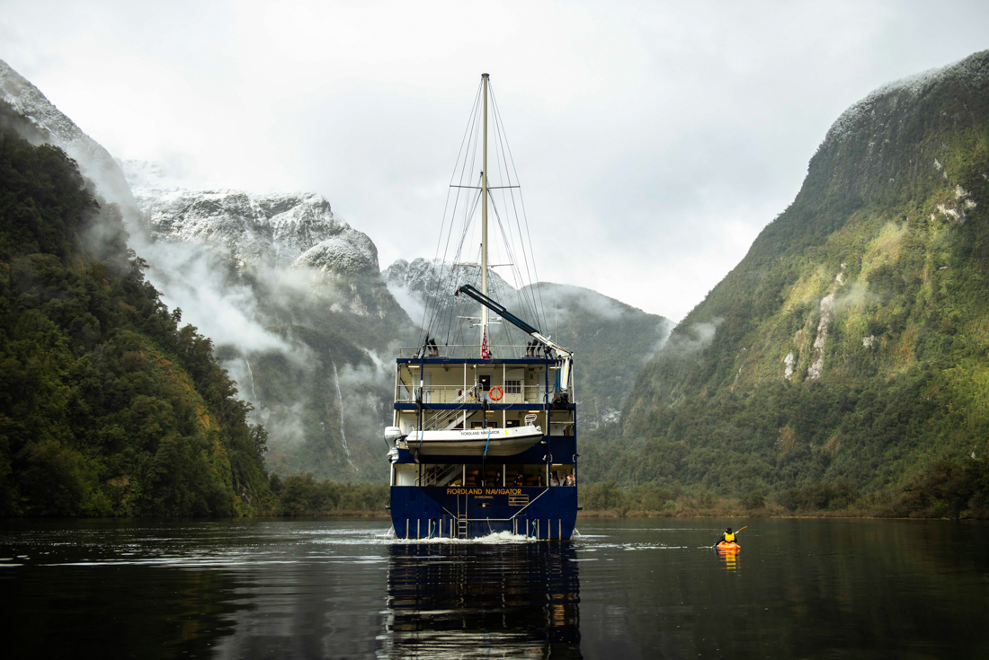 Clouds roll down from the peaks of Doubtful Sound as the Fjordland Navigator sails through in New Zealand