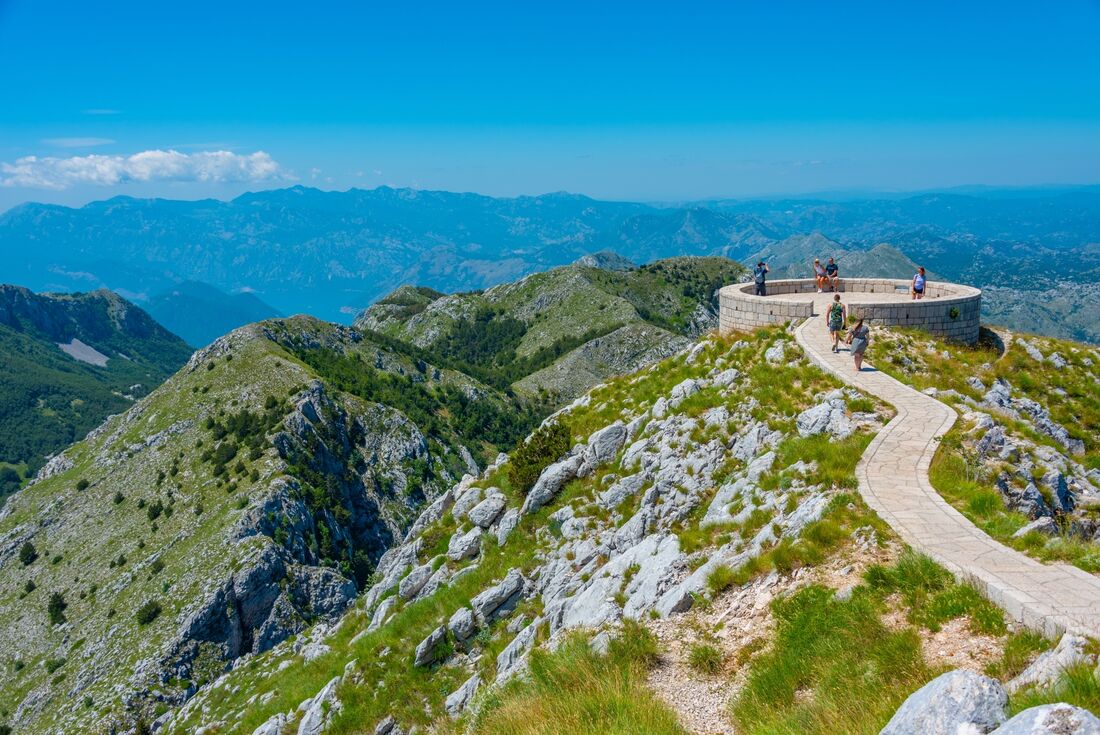 Wide shot of travellers walking on stone path along a rocky mountain in Lovcen National Park in Cetinje, Montenegro