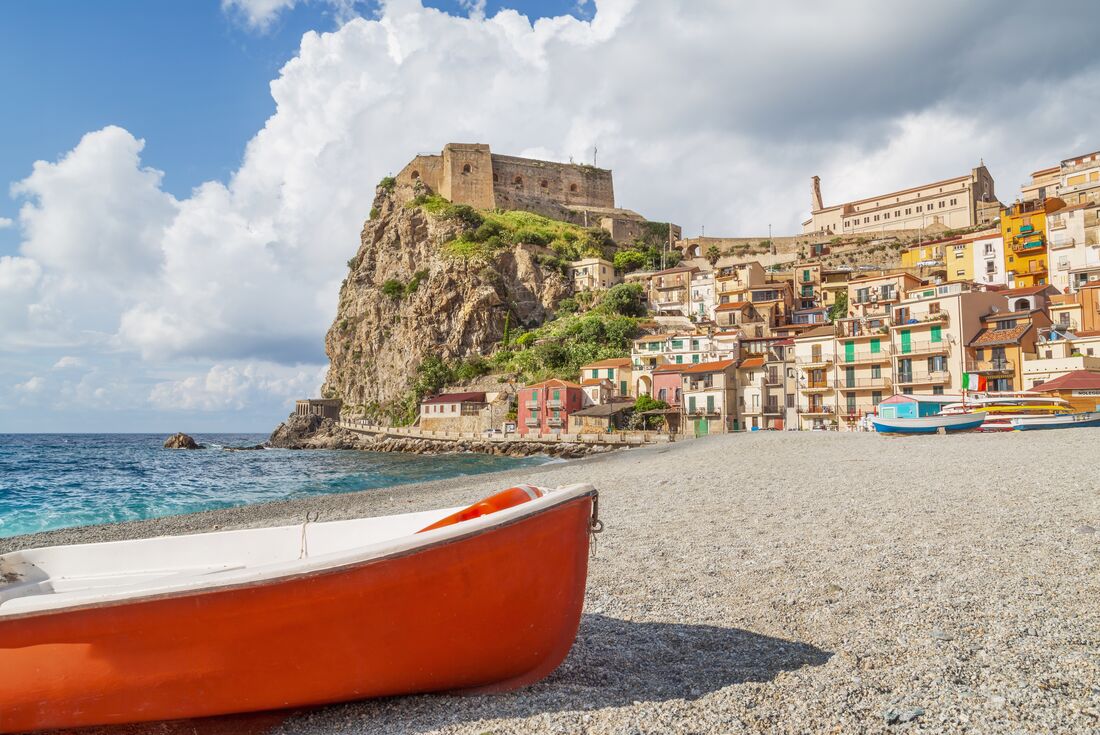 A boat pulled onto the beach of Tropea with Castello Ruffo beyond on a rock outcropping