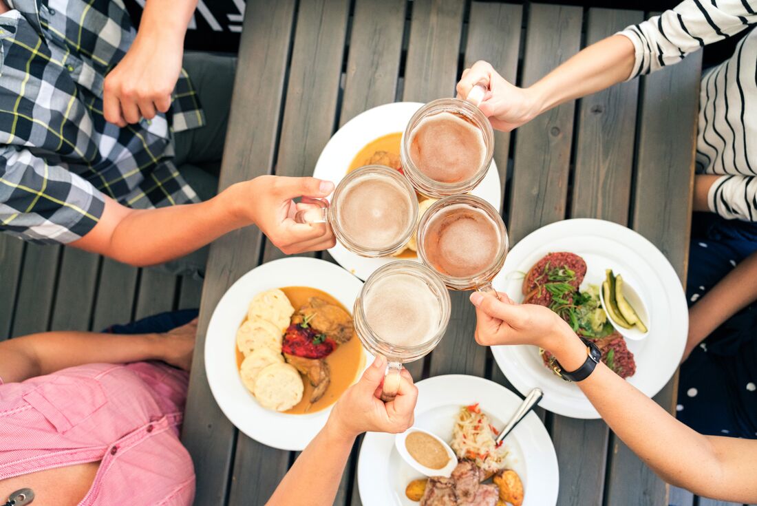 Intrepid travellers cheers czech pilsners in glass mugs over plates of food