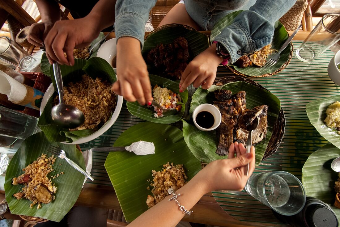Top down shot of travellers sharing a filipino meal with banana leaves