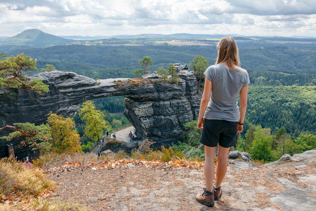 Intrepid traveller stands high taking in Presbischtor Gate in Czechia's mountains