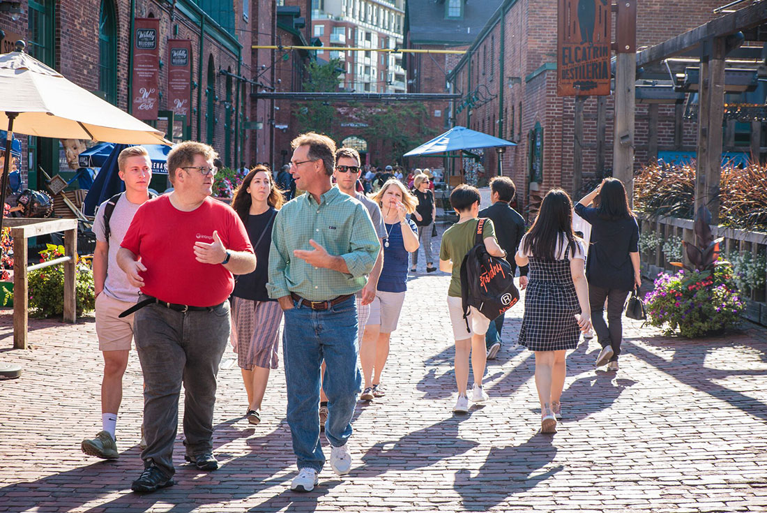 Intrepid leader heads group talking to travellers walking the streets of Toronto's distillery district 