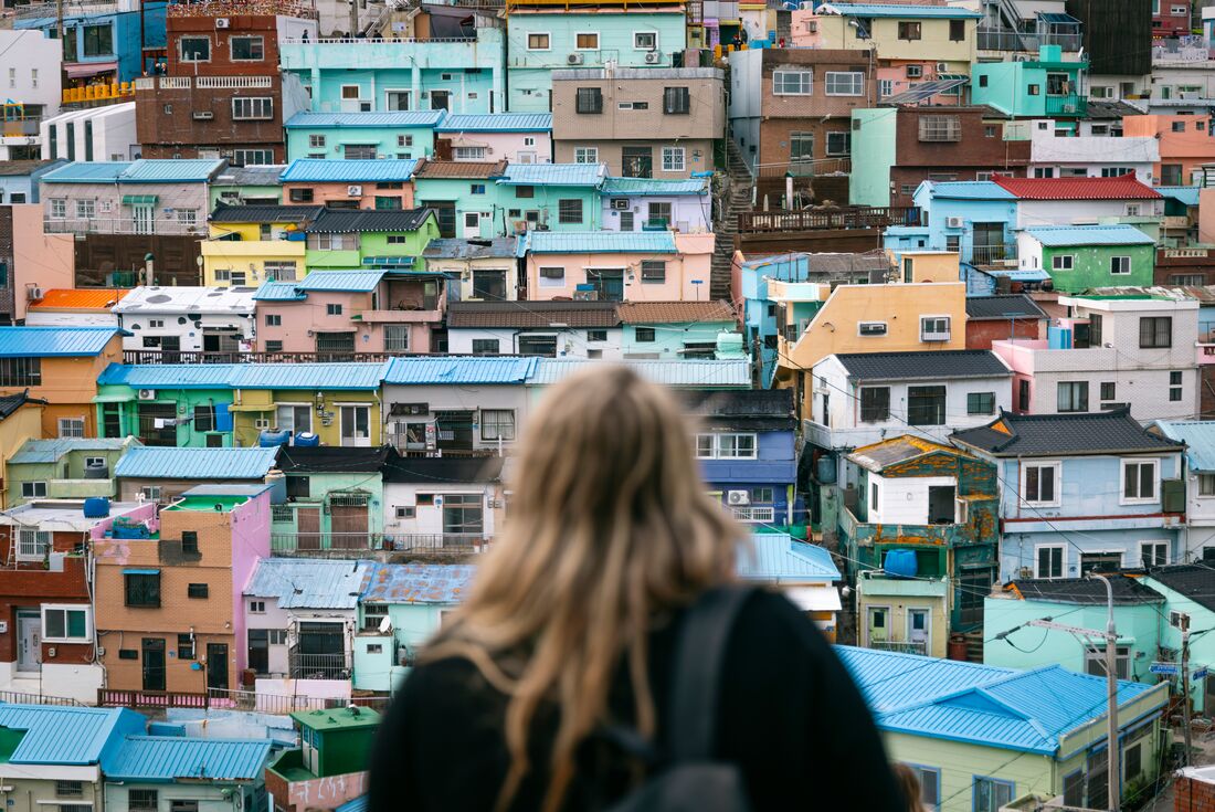 Traveller looks out at colourful facades of pastel houses at an overlook in Gamcheon Culture Village