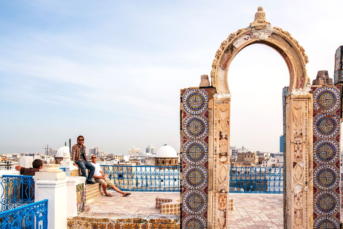 Rooftop relaxation in Tunis's Medina among tiled gates and city views
