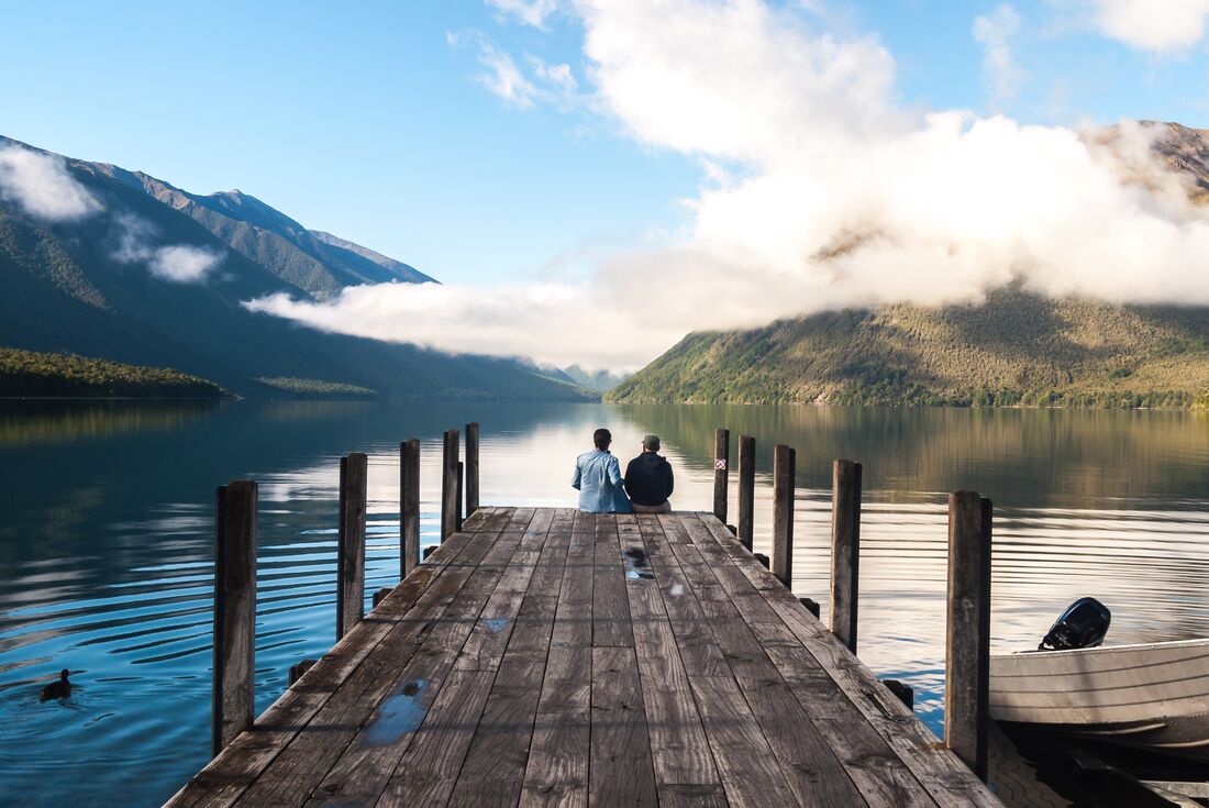 Travellers sit at the end of a pier on Lake Rotoiti in Nelson Lakes National Park in New Zealand