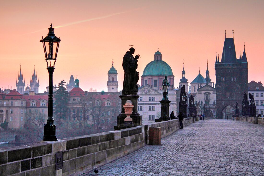 Sunrise glow creeps over the ancient city of Prague, seen from the storied Charles Bridge in Czechia