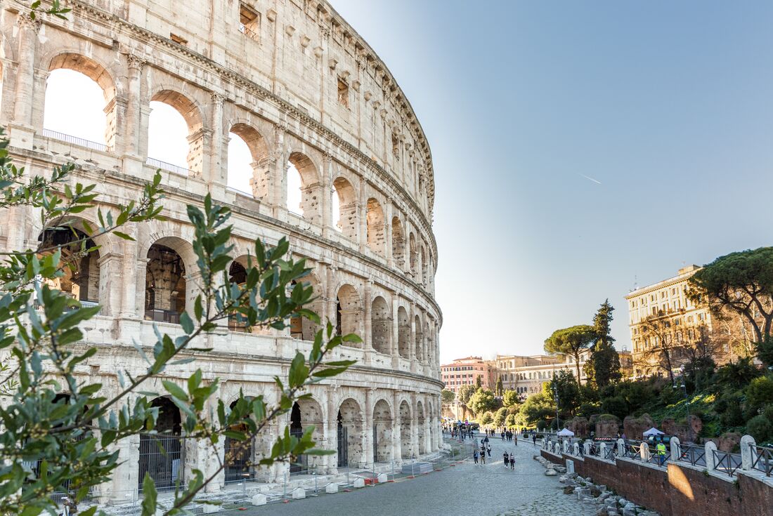 Iconic facade of Rome's Colosseum curves away from the camera with tiny crowds below for scale