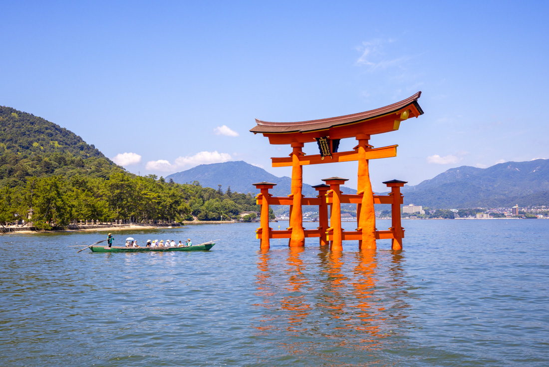 Itsukushima Shrine in the bay off Miyajima Island with a boat full of travellers approaching in Japan