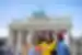Four 18 to 35s travellers in colourful outfits take a selfie in Berlin near the Brandenburg Gate