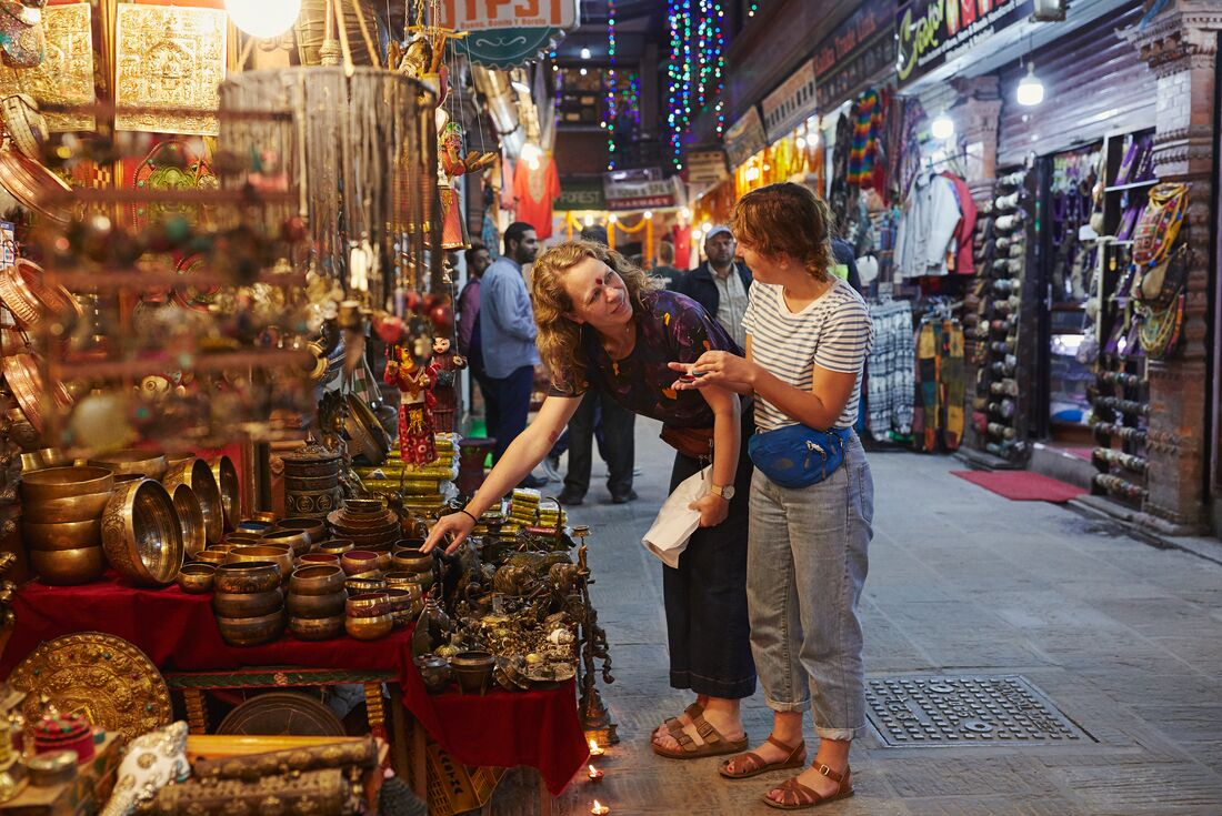 Travellers looking at brass homewares at a street market in Kathmandu, Nepal, at night