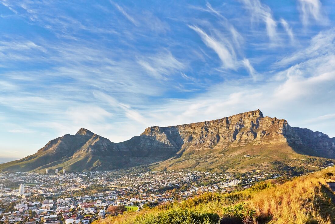 Huge face of Table Mountain being hit by the morning sun sits over Cape Town's northern side at sunrise
