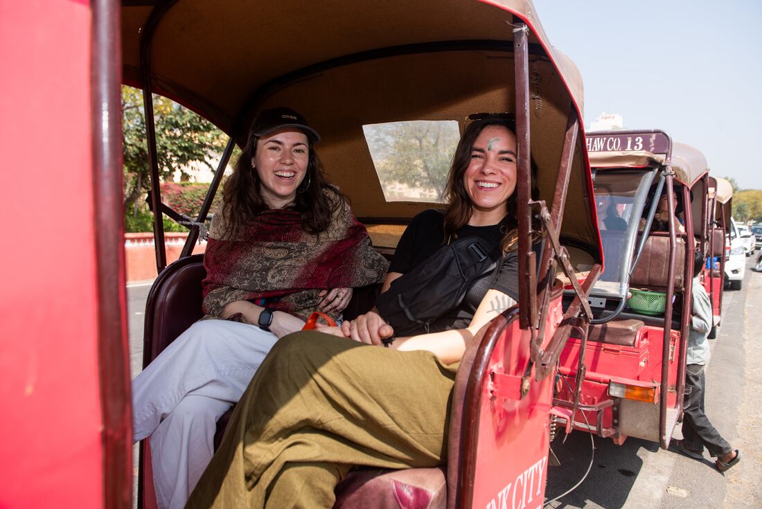 Two travellers smiling while enjoying a ride in a rickshaw, Jaipur, India
