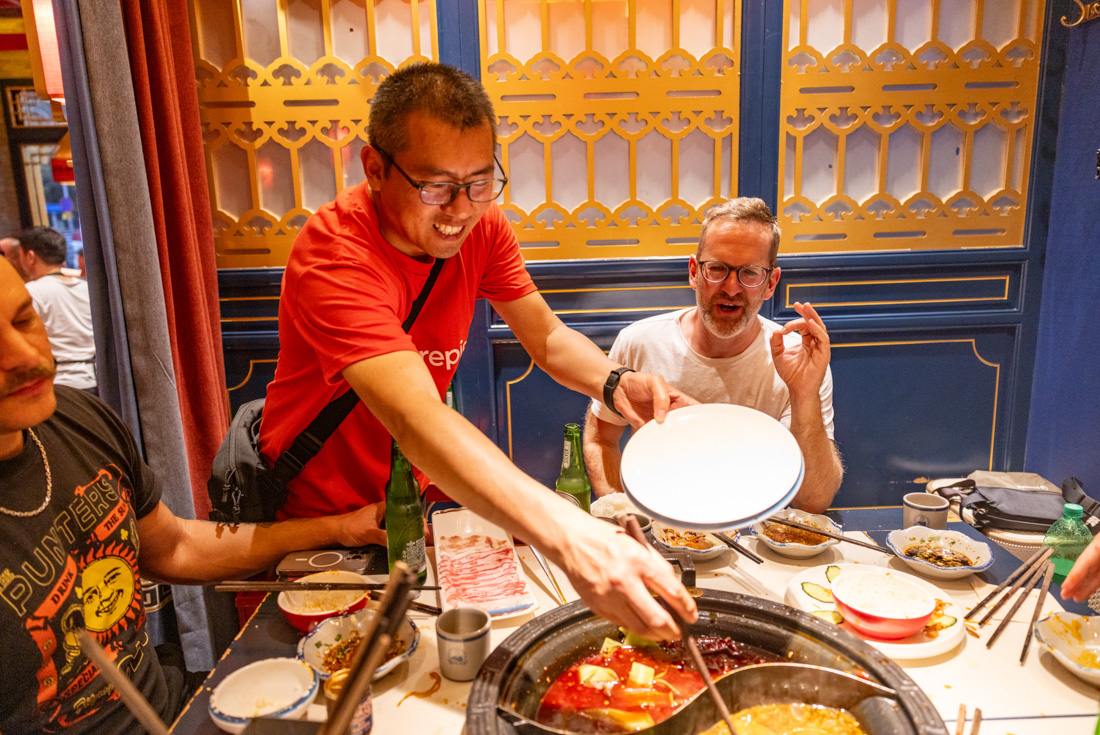 Intrepid leader stirs a sichuan hotpot for a traveller in Chengdu China