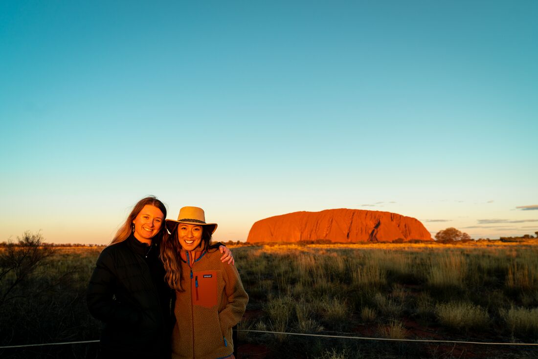Intrepid travellers pose happily together during a sunset viewing at Uluru in Northern Territory Australia
