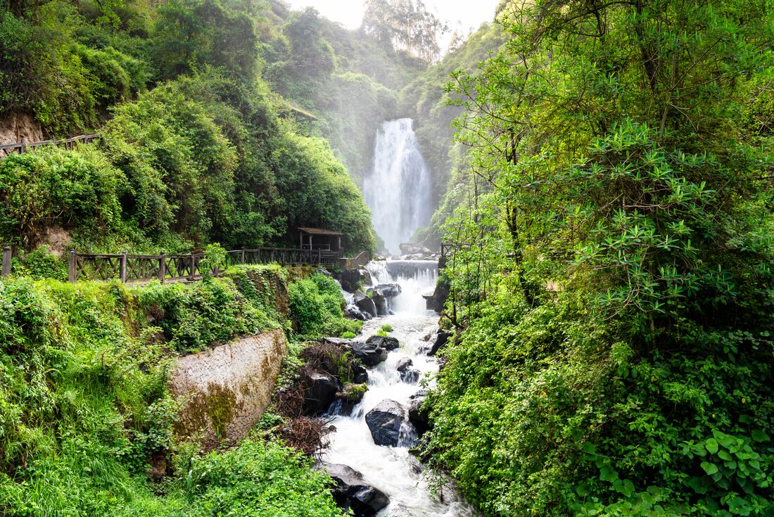 View of Peguche Waterfall surrounded by green vegetation in Ecuador