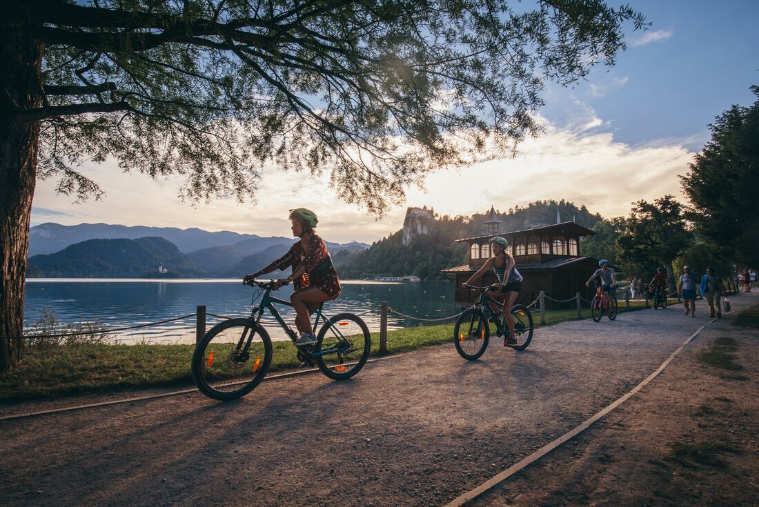 A group of cyclists riding their bikes around the stunning Lake Bled at dusk in Slovenia