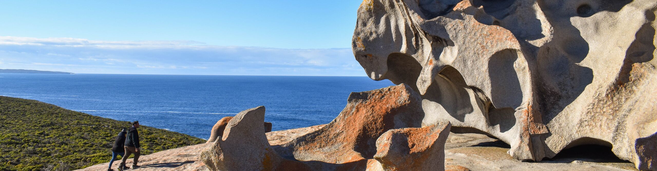 A close up of the Remarkable rocks with walkers, blue ocean and green valley