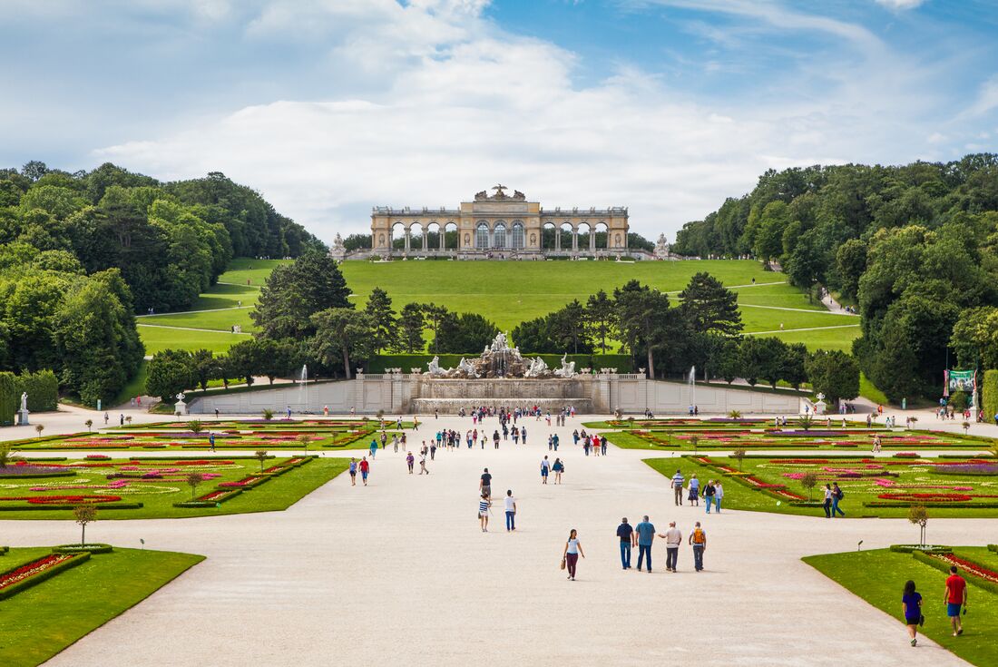 Travellers and locals wander the curated gardens of Schonbrunn Palace in Vienna Austria