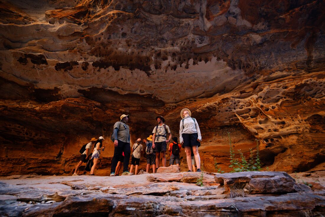 Travellers and leader marvel at the rock faces of a cave in Cathedral Gorge walk