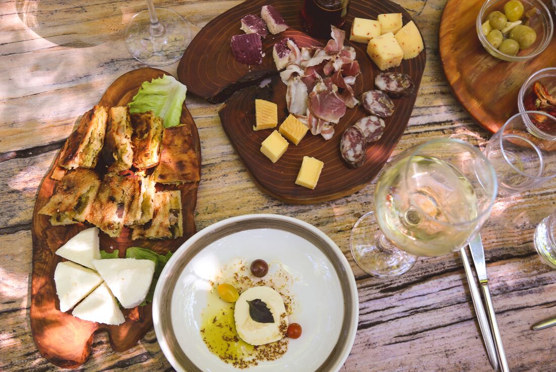 Plates of cured meats, cheese, and artisinal breads and wine at Mrizi i Zanave in Albania