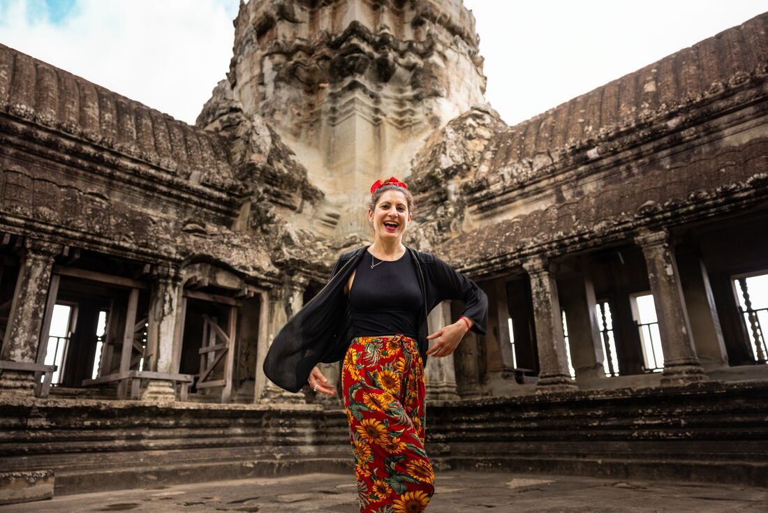 Traveller smiling in front of one of the corners of Angkor Wat, showing the intricate architecture, Siem Reap, Cambodia