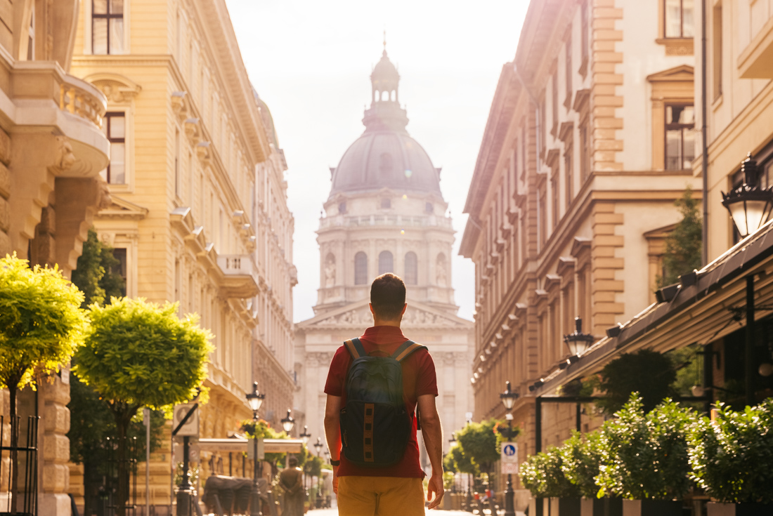 Traveller approaches St Stephen's Basilica down a planted street in Budapest in summer