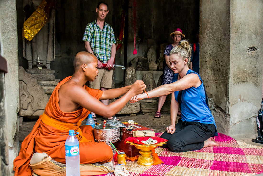 Traveller receiving a blessing wristband from a Buddhist monk in Siem Reap, Cambodia on an Intrepid Travel tour