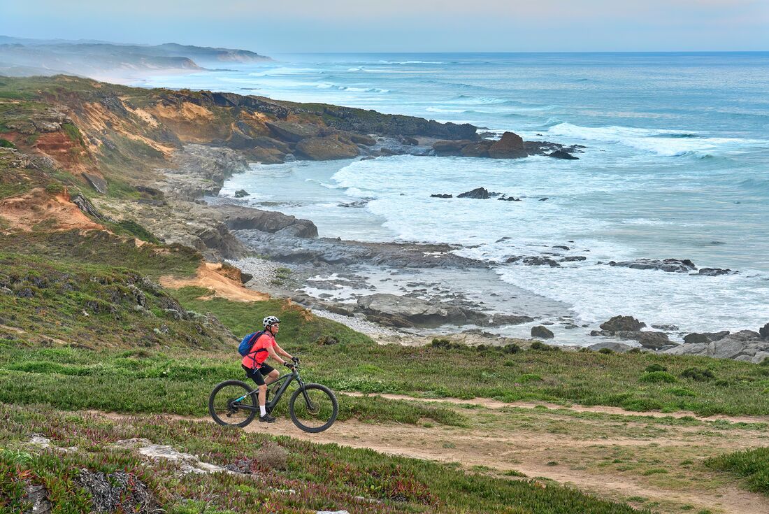 Traveller cycling along coastline in Porto, Portugal