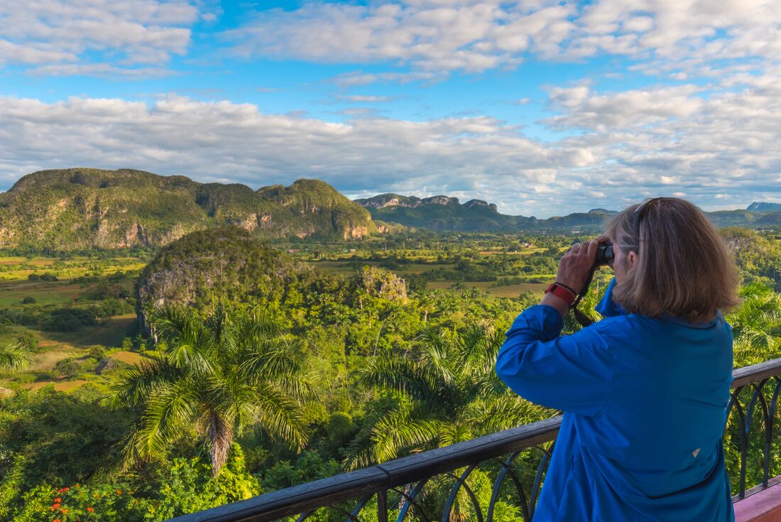 Traveller looking out over Vinales Valley with biioculars in the beautiful green belt of Cuba