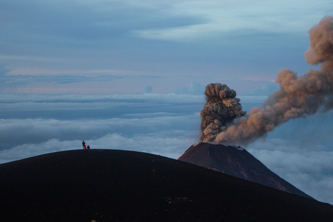 Intrepid travellers stop on the peak of Acatenango watching Volcano Fuego erupt in Guatemala