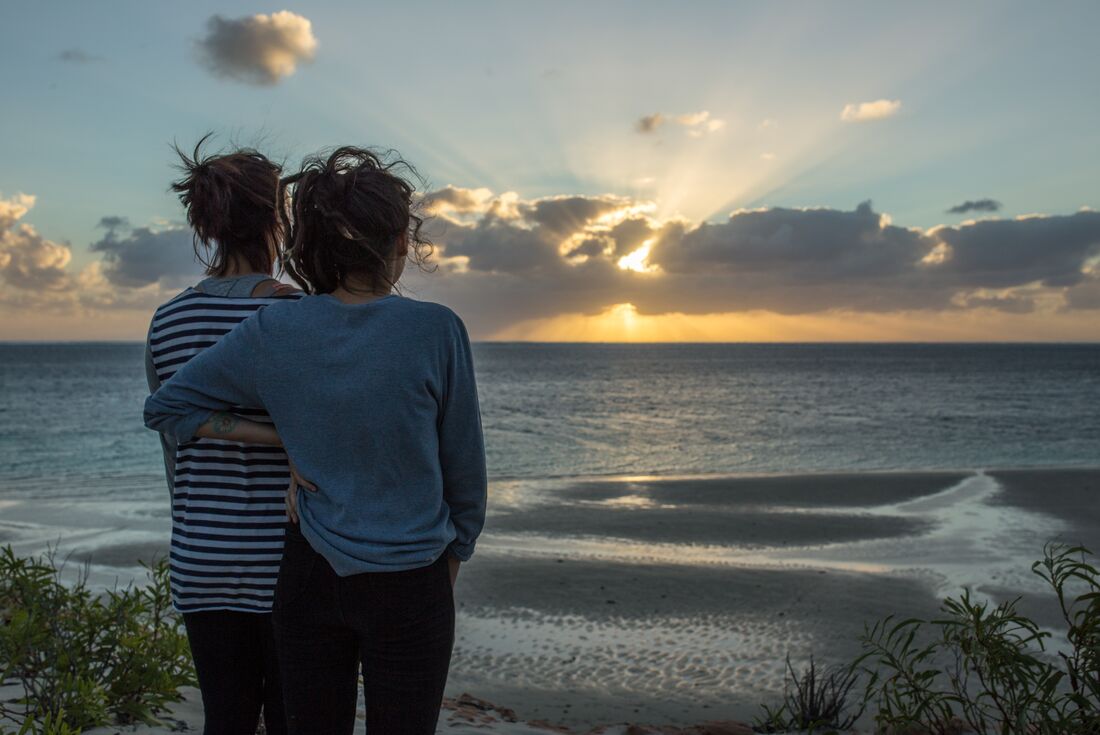 Travellers looking out at Coral Bay at sunset
